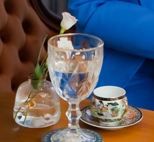 Mesa com xícara de chá, taça e uma rosa branca